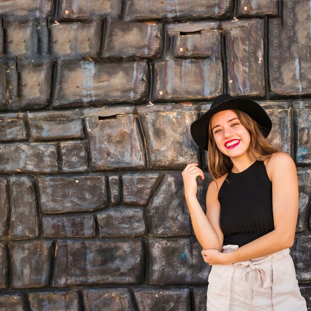 Mujer joven hermosa moderna que se coloca en el frente de la pared