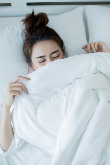 Mujer joven hermosa que se acuesta en la cama y dormir.