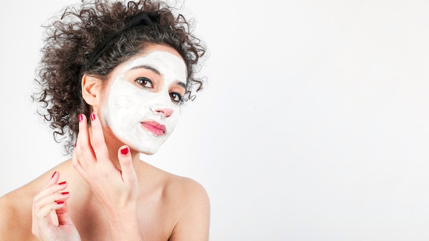 Mujer joven hermosa que aplica la crema cosmética en su cara