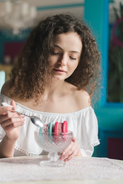 Mujer joven hermosa que come los bocadillos del helado con la cuchara