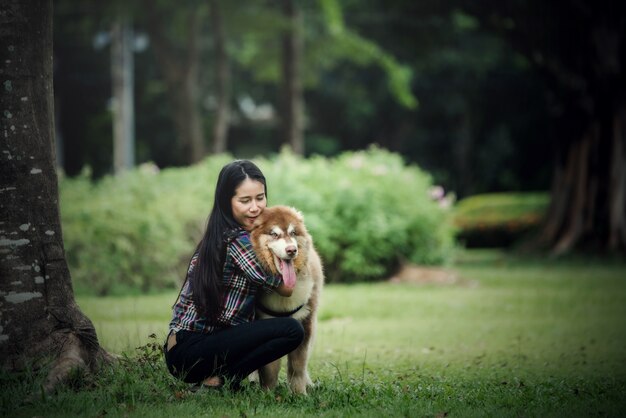 Mujer joven hermosa que juega con su pequeño perro en un parque al aire libre. Retrato de estilo de vida