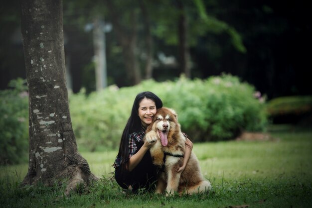 Mujer joven hermosa que juega con su pequeño perro en un parque al aire libre. Retrato de estilo de vida