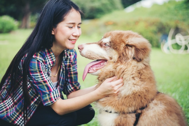 Mujer joven hermosa que juega con su pequeño perro en un parque al aire libre. Retrato de estilo de vida