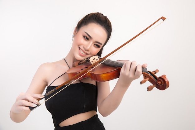 Mujer joven hermosa que toca el violín sobre el fondo blanco