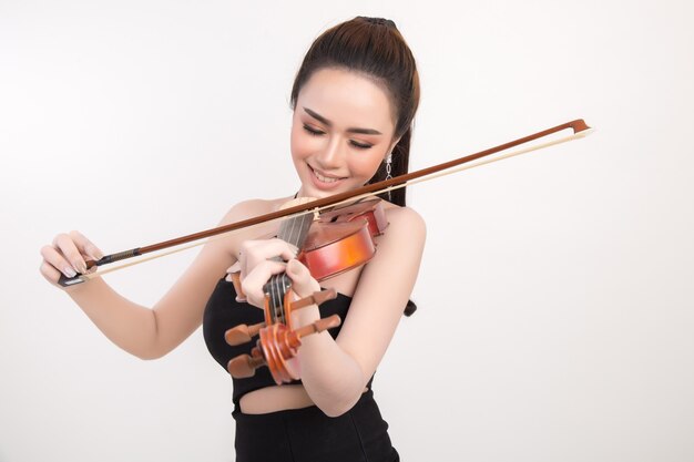 Mujer joven hermosa que toca el violín sobre el fondo blanco