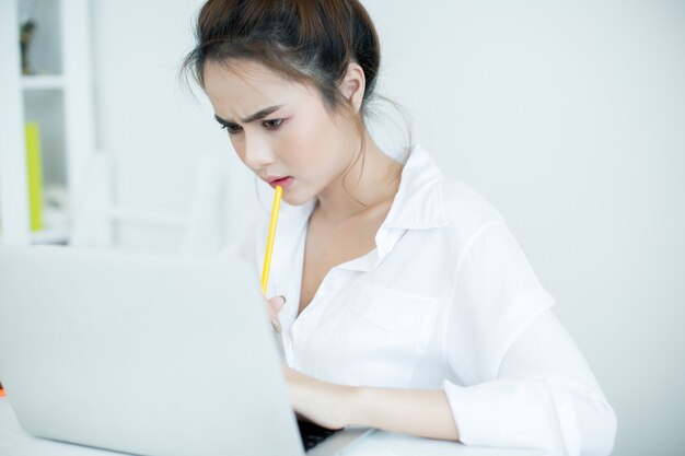 Mujer joven hermosa que trabaja en su computadora portátil en su sitio.