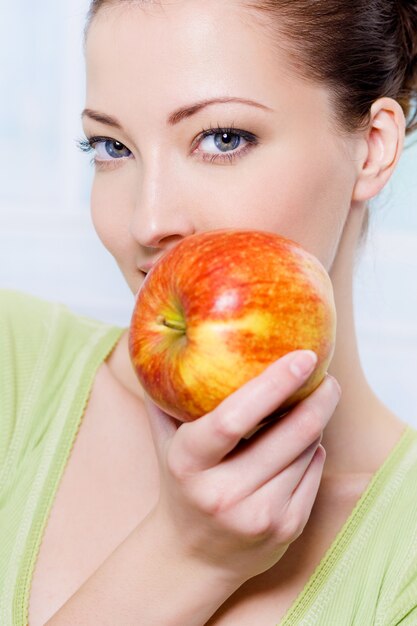 Mujer joven hermosa sensibilidad con manzana - en el interior