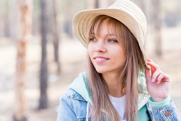 Mujer joven hermosa en el sombrero que mira lejos al aire libre