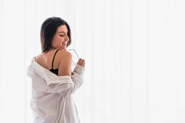 Mujer joven hermosa sonriente que se coloca delante de la cortina