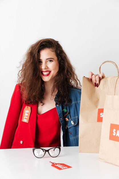 Mujer joven hermosa venta sentado con bolsas de papel