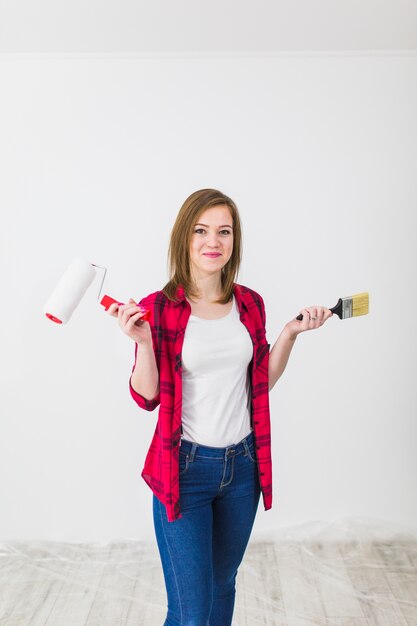 Mujer joven con herramientas de pintura mirando la cámara