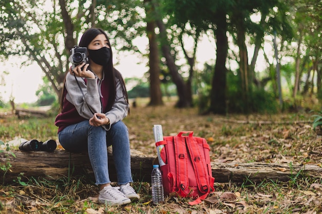 Mujer joven hippie con mascarilla tomando fotografías.