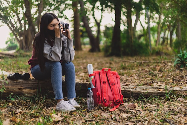 Mujer joven hippie con mascarilla tomando fotografías.