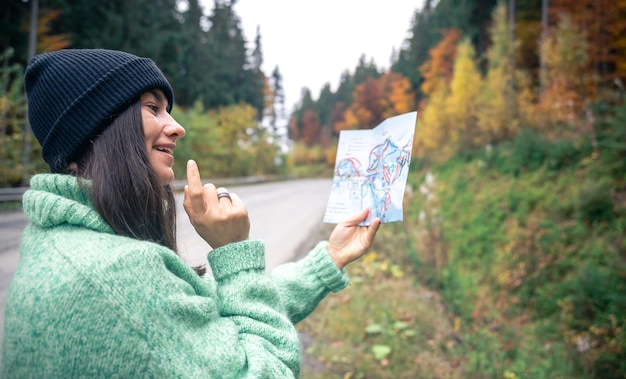 Una mujer joven con una hoja de ruta en el bosque de las montañas