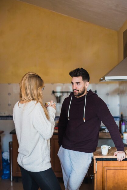 Mujer joven y hombre hablando en la cocina