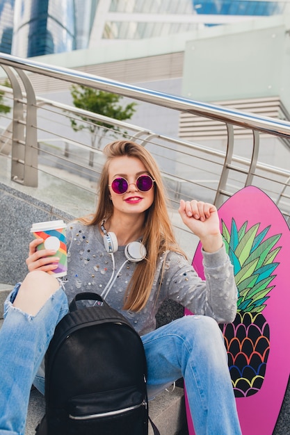 Mujer joven inconformista en la calle con tabla de equilibrio vistiendo suéter y jeans