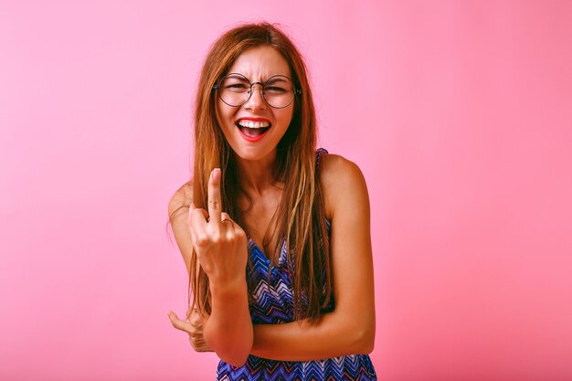 Mujer joven inconformista divertido que muestra dos dedos medios, ella está enojada contigo, concepto agresivo.