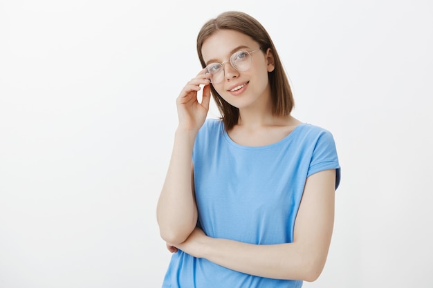 Mujer joven inteligente en vasos sonriendo complacido