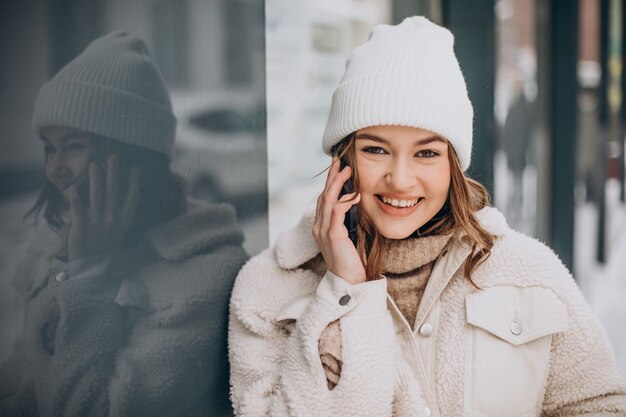 Mujer joven en invierno con teléfono fuera de la calle