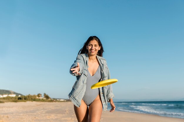 Mujer joven jugando frisbee en la playa del resort