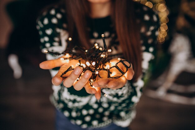 Mujer joven junto al árbol de Navidad con luces brillantes de Navidad