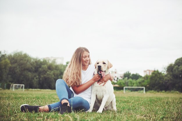 mujer joven con labrador al aire libre. Mujer sobre una hierba verde con perro labrador retriever.