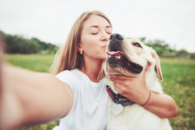 mujer joven con labrador al aire libre. Mujer sobre una hierba verde con perro labrador retriever.