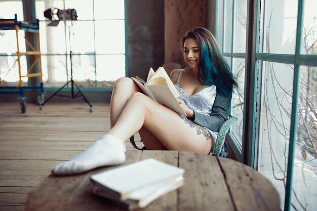 Mujer joven, lectura, libro, sentado, cerca, ventana