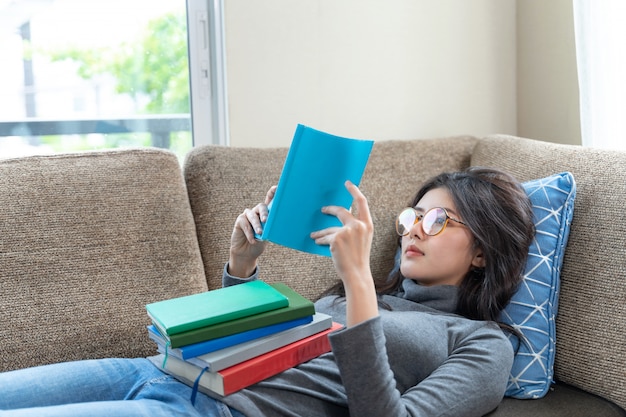 Mujer joven, lectura, libro de texto, en, sofá, en casa