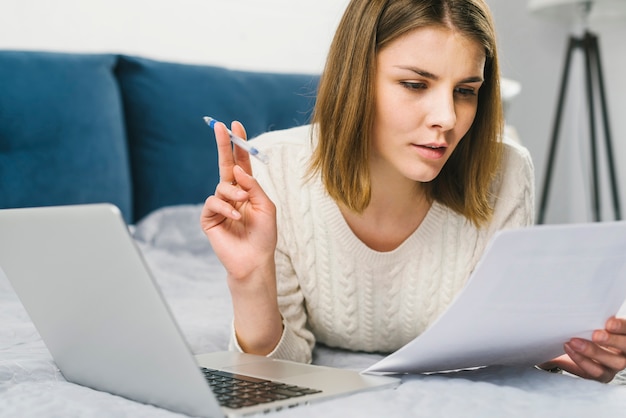 Mujer joven leyendo documentos en la cama