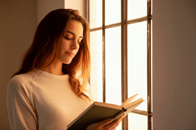 Foto gratuita mujer joven leyendo un libro en casa