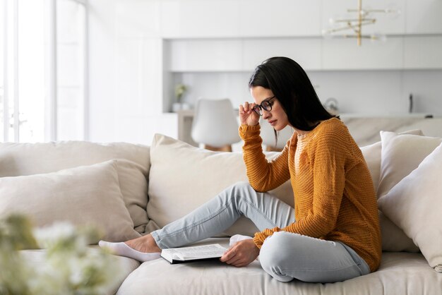 Mujer joven leyendo un libro en casa