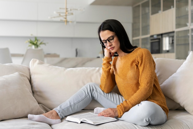 Mujer joven leyendo un libro en casa