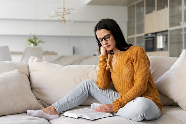 Mujer joven leyendo un libro en casa