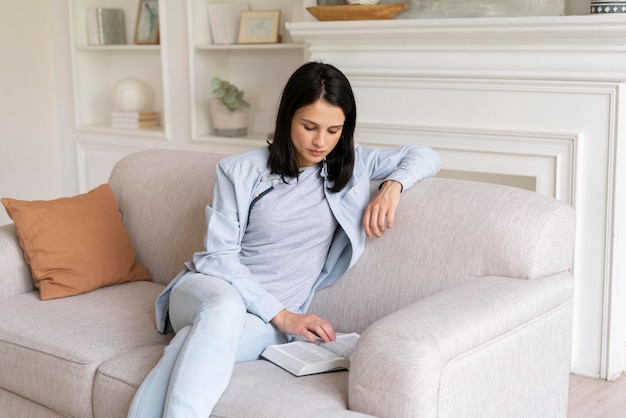 Mujer joven leyendo un libro en casa