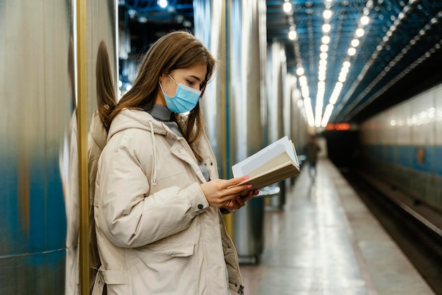 Mujer joven leyendo un libro en una estación de metro