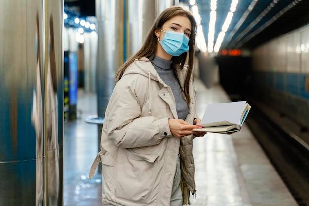 Mujer joven leyendo un libro en una estación de metro