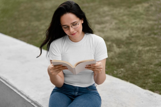 Foto gratuita mujer joven leyendo un libro interesante