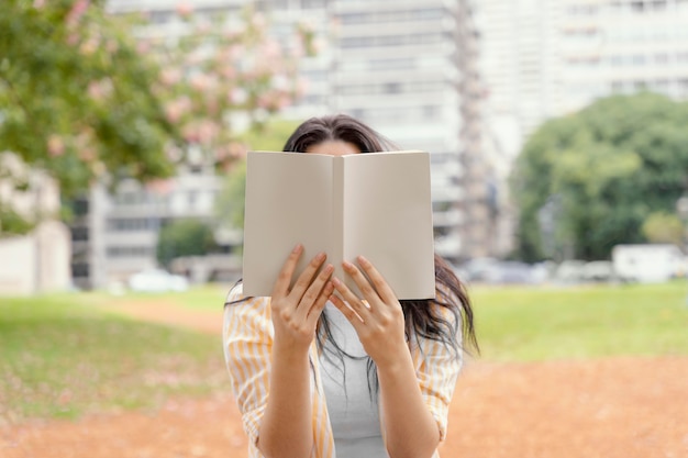 Foto gratuita mujer joven leyendo un libro interesante