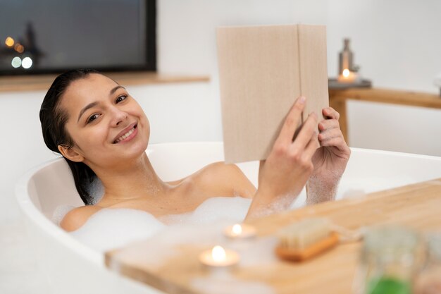 Mujer joven leyendo un libro mientras toma un baño