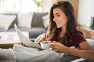Foto gratuita mujer joven leyendo el periódico y tomando café