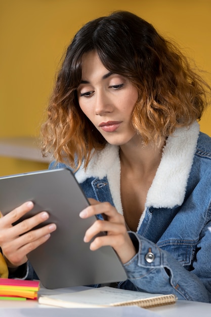 Mujer joven leyendo desde la tableta durante la sesión de estudio