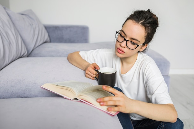 Mujer joven con libro de lectura de bebidas