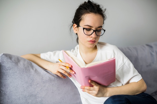 Mujer joven con libro de lectura de lápiz