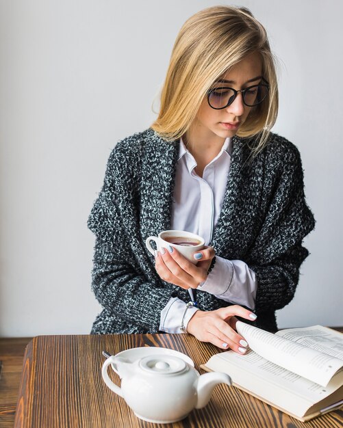 Mujer joven con libro de lectura de té