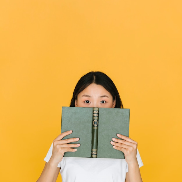 Foto gratuita mujer joven con un libro mirando a la cámara