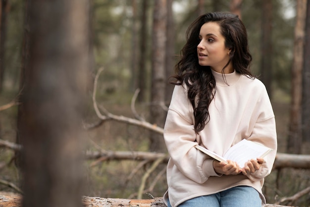 Mujer joven con libro en la naturaleza