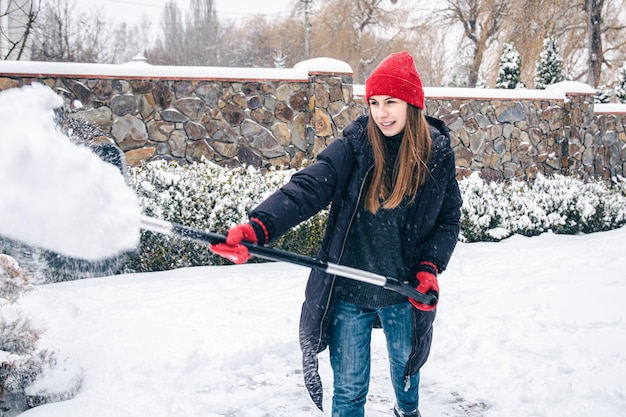 Foto gratuita mujer joven limpia la nieve en el patio en tiempo de nieve