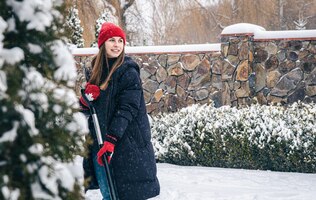 Foto gratuita mujer joven limpia la nieve en el patio en tiempo de nieve