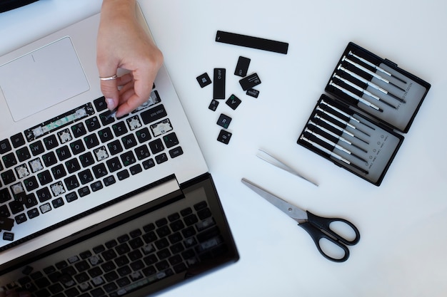 Foto gratuita mujer joven limpiando el teclado de su computadora portátil